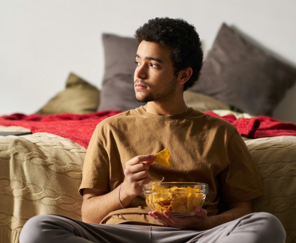 Young guy eating chips at home